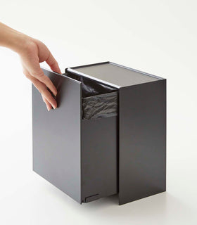 Person adjusting bin drawer on black Wall-Mount Storage on white background by Yamazaki Home. view 13