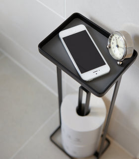 Close up aerial view of black Toilet Paper Stocker holding phone, clock, and toilet paper in bathroom by Yamazaki home. view 7