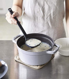 Front view of black Floating Ladle scooping soup out of pot by Yamazaki Home. view 3