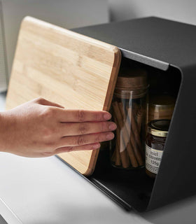 Black Yamazaki Bread Box with Cutting Board Lid being opened partially with jam and spices inside view 13