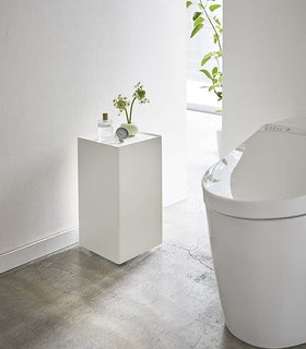 White Rolling Bathroom Organizer holding decor in bathroom by Yamazaki Home. view 2