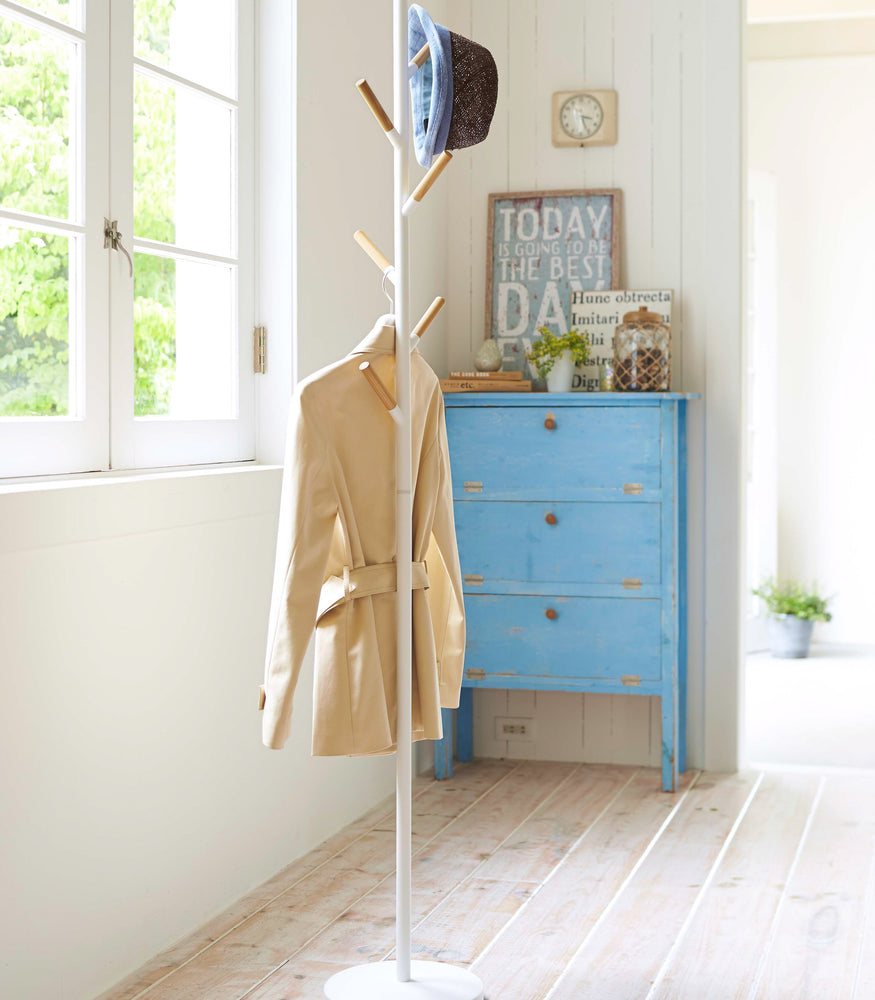 View 2 - White Freestanding Coat Rack displaying jacket and hat by Yamazaki Home.