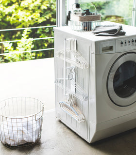 White Magnetic Clothes Hanger Organizer holding hangers in laundry room by Yamazaki Home. view 2