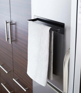 Black Magnetic Paper Towel Holder holding dish towel in kitchen by Yamazaki Home. view 10