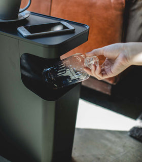 Close up view of black Side Table Trash Can holding phone and plastic bottle by Yamazaki Home. view 9