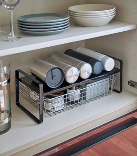 Black Expandable Countertop Organizer expanded holding bottles in kitchen cabinet by Yamazaki Home. view 8