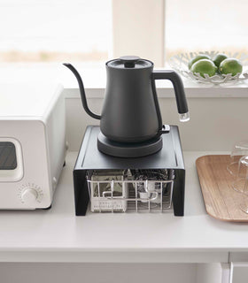 Frontal veiw of black Yamazaki Home Stackable Countertop Shelf with a kettle above and a basket of tea underneath view 15