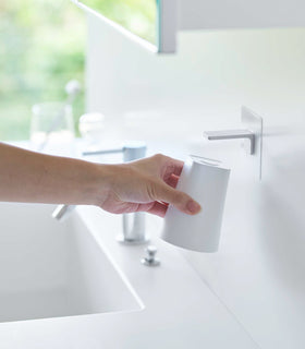 Removing white Yamazaki Home traceless adhesive magnetic cup installed next to sink view 3