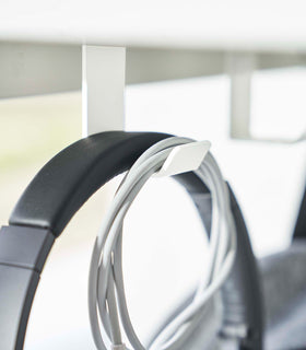 Close-up view of a matte white metal hook securely attached to the underside of a wooden table. view 4