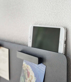 Closeup of a phone resting on top of a Yamazaki black Magnetic Wall Panel view 13