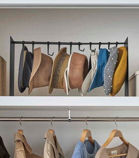 Frontal view of black Yamazaki Home hat rack hanging a variety of hats in a closet view 15