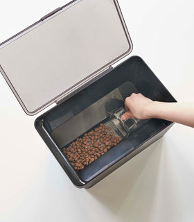 Aerial view of person scooping pet food out of black Airtight Food Storage Container on white background by Yamazaki Home. view 23