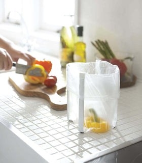 Small white Yamazaki Collapsible Bottle Dryer with a bag held for veggie scraps view 2