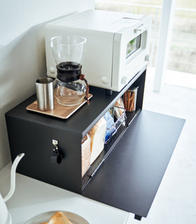 Close up side view of black Yamazaki Home Bread Box - Wide open on a counter with bread and snacks inside view 13