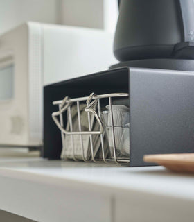 Close up of black Yamazaki Home Stackable Countertop Shelf with a basket underneath view 16