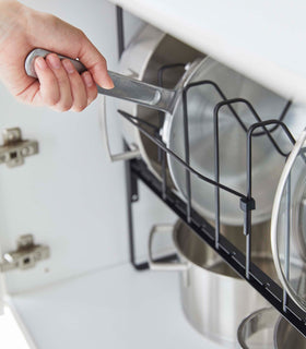 A pan being pulled from a black Yamazaki Home Adjustable Pots and Pans Organizer view 13