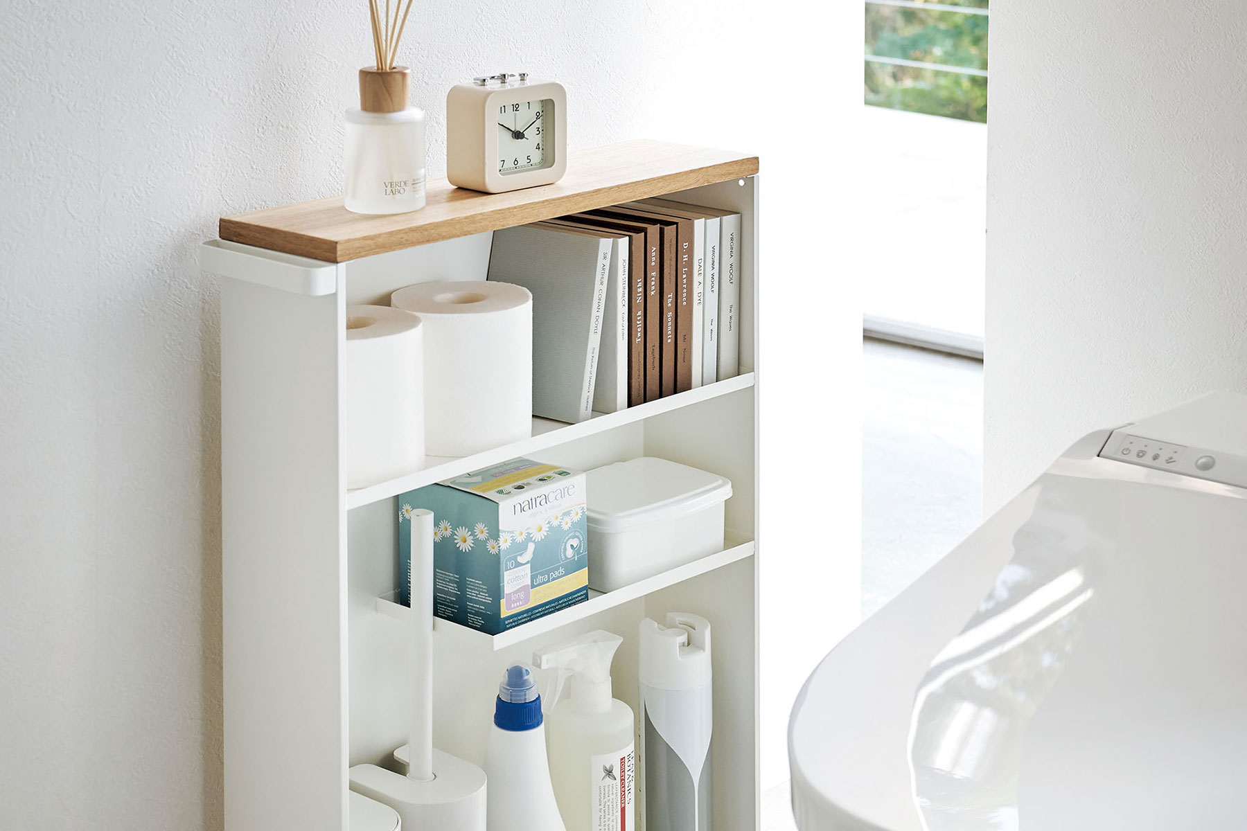 White Rolling Storage Cart in the bathroom and holding bathroom items/accessories by Yamazaki Home.