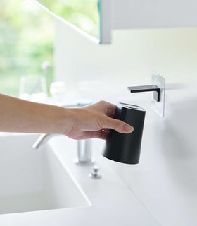 Removing white Yamazaki Home traceless adhesive magnetic cup installed next to sink view 7