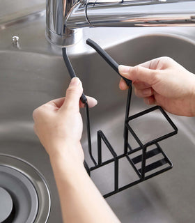 Black Steel Yamazaki Home Faucet-Hanging Sponge & Brush Holder being installed to a faucet view 13