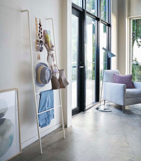 Side view of white Leaning Ladder with Grid Panel holding accessories in living room by Yamazaki Home. view 2