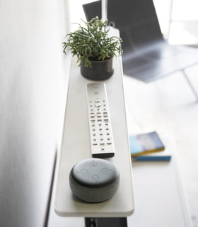 Side view of white Compliant TV Shelf holding smart home device, plant, and remote by Yamazaki Home. view 4