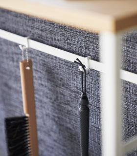 Items hanging form hooks on the back bar of the Long Console Table by Yamazaki Home in white. view 6