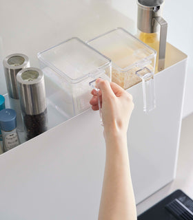 Close up of top of white Yamazaki Home Sliding Seasoning Rack with food containers stored view 4