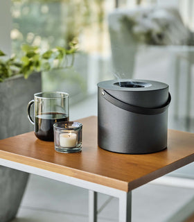 Black Yamazaki Mosquito Repellant Coil Holder and Storage Case lit on a table outside view 2