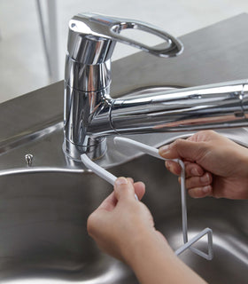 White Faucet-Hanging Sponge Holder attatching to sink faucet by Yamazaki Home. view 3