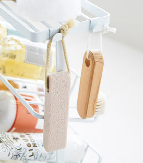 Close up corner view of white Freestanding Shower Caddy hooks holding sponge and brush by Yamazaki Home. view 11