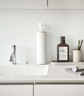 Small white Yamazaki Home Round Tissue Case on a bathroom sink counter view 8