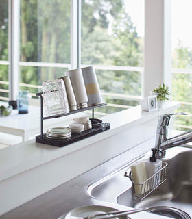 Black Countertop Bottle Drying Rack holding bottles and covers in kitchen by Yamazaki Home. view 10