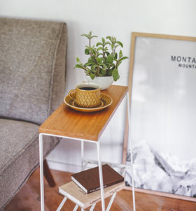 Side view of white End Table holding coffee cup, plant, and books by Yamazaki Home. view 3