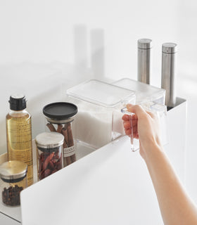 Close up of removing spices off the top of white Yamazaki Home Two-Tier Sliding Drawer Seasoning Rack view 6