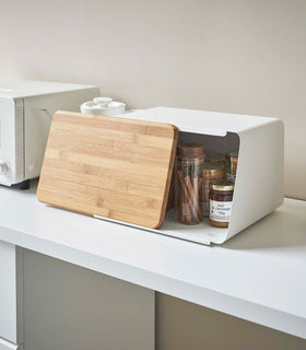 White Yamazaki Bread Box with Cutting Board Lid partially open with spices and jam inside view 2